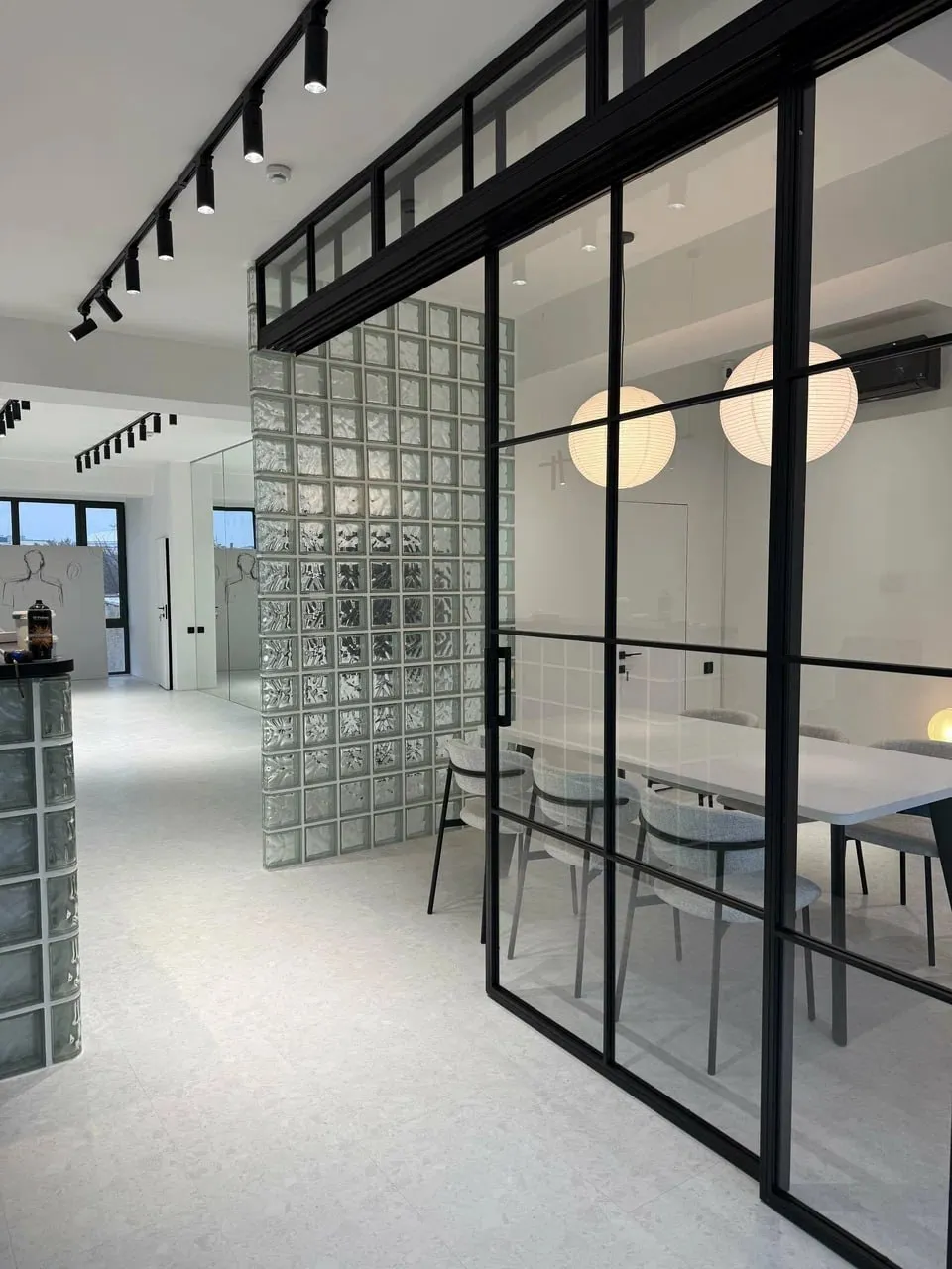 The Mariotto Management office: a bright hall with a glass-block wall and a meeting room behind black frames.